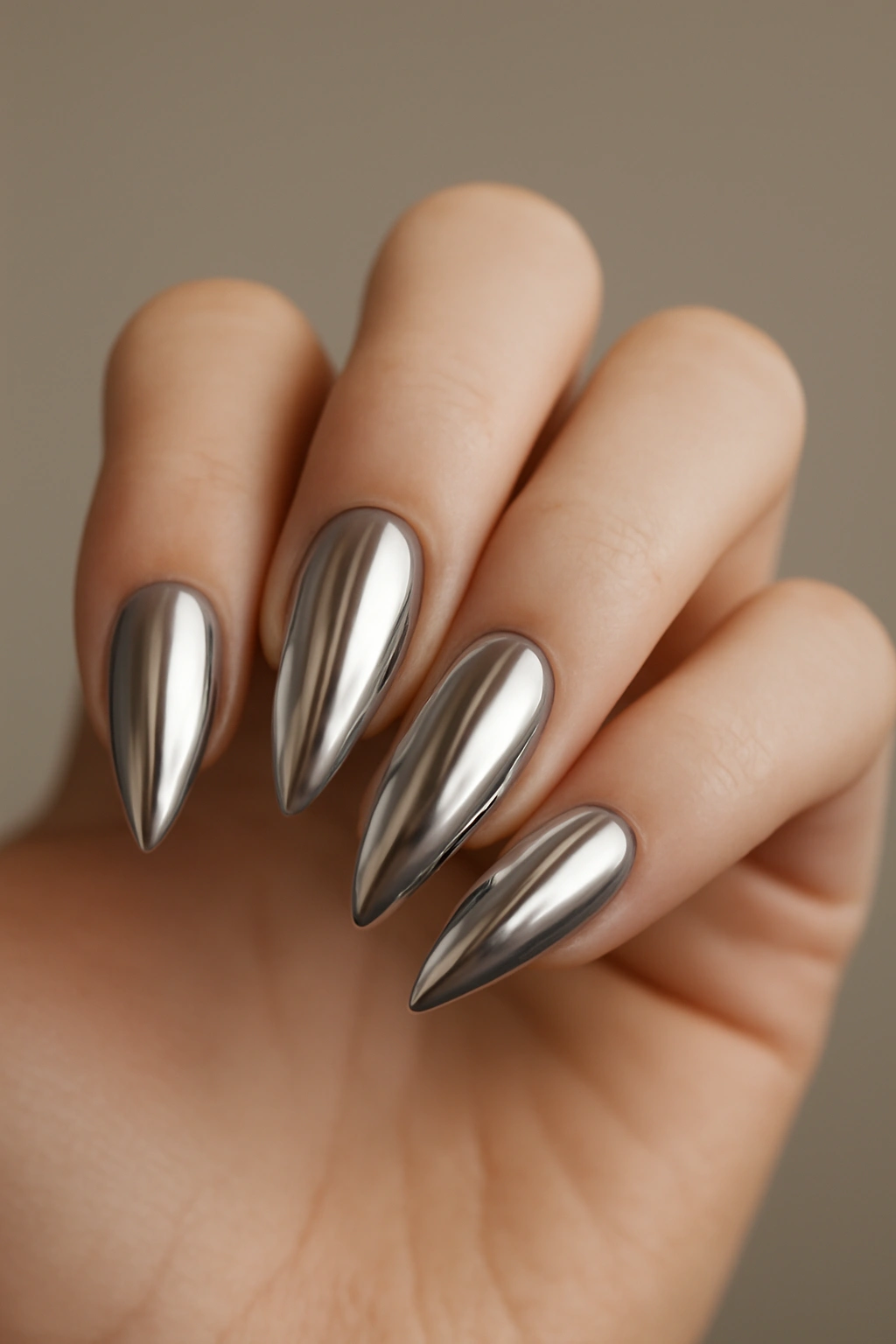 Close-up of almond-shaped chrome nails with mirror finish on a hand