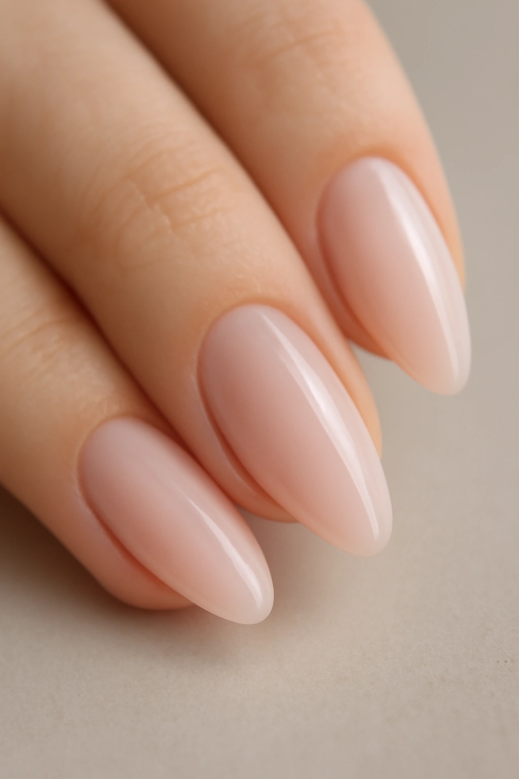 Close-up of an almond-shaped nail with sheer pink polish on natural nail